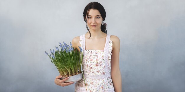 Bella giovane donna che tiene i fiori di primavera in vaso di fiori guardando la parte anteriore