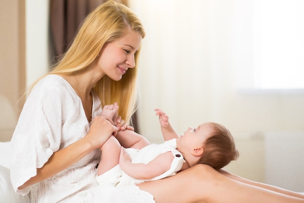 Bella giovane donna che tiene la bambina tra le braccia nella stanza domestica al mattino