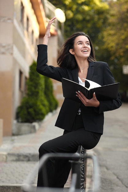 Bella giovane donna che tiene un taccuino nelle sue mani sul concetto di strada dello stile di vita aziendale o educativo