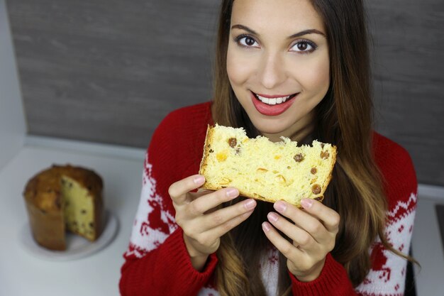 Bella giovane donna che tiene una fetta di panettone durante le vacanze di Natale