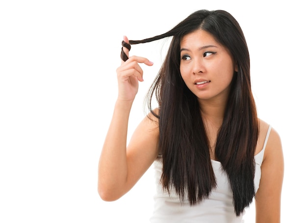 Bella giovane donna che tocca i capelli lunghi mentre si trova contro uno sfondo bianco
