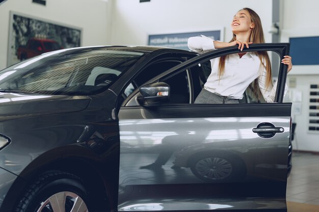 Bella giovane donna che tocca la sua nuova automobile con piacere