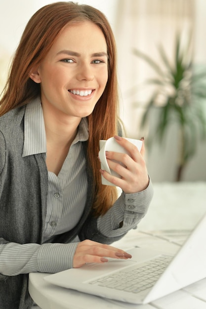 Bella giovane donna che utilizza il computer portatile al tavolo