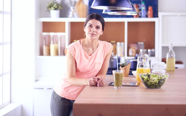 Bella giovane donna che utilizza una tavoletta digitale in cucina