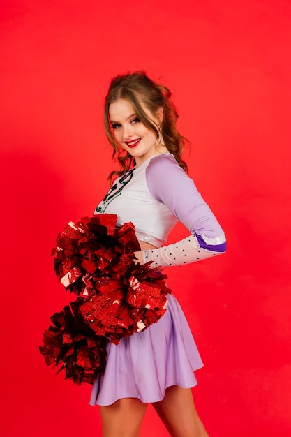 Bella giovane donna cheerleader adulta, sfondo rosso e blu dello studio