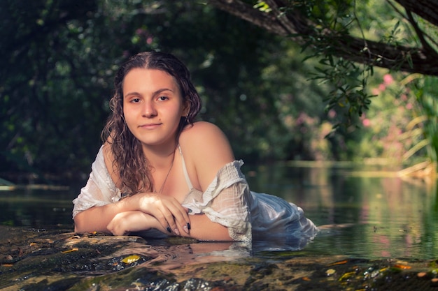 Bella giovane donna con abito bianco vicino al flusso d'acqua.