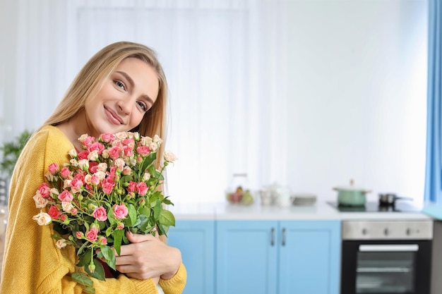 Bella giovane donna con bouquet di rose a casa