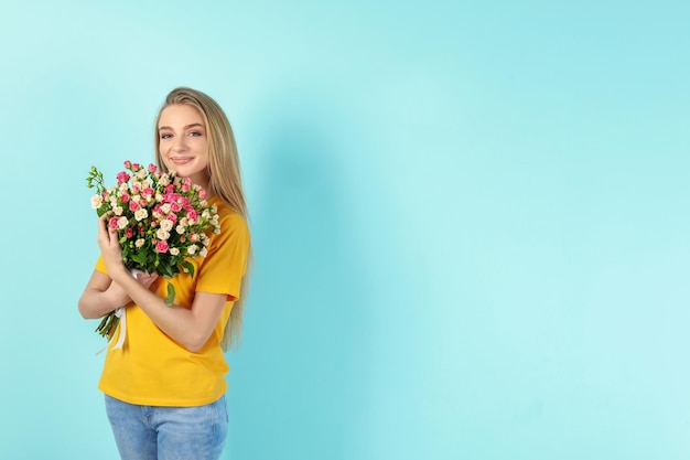 Bella giovane donna con bouquet di rose su sfondo colorato