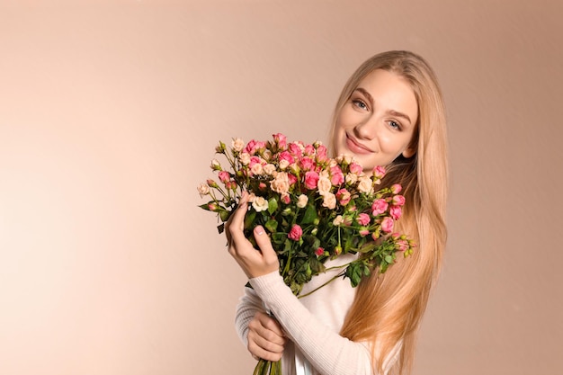 Bella giovane donna con bouquet di rose su sfondo colorato