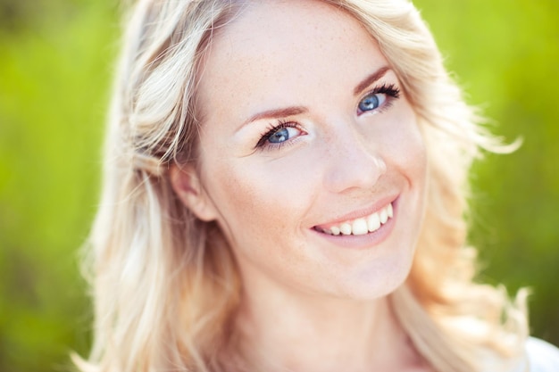 Bella giovane donna con capelli biondi e denti bianchi all'aperto cercando fotocamera ar.