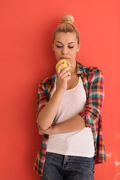 bella giovane donna con capelli chignon gioca con la mela su sfondo colorato con copyspace che esprime emozioni diverse