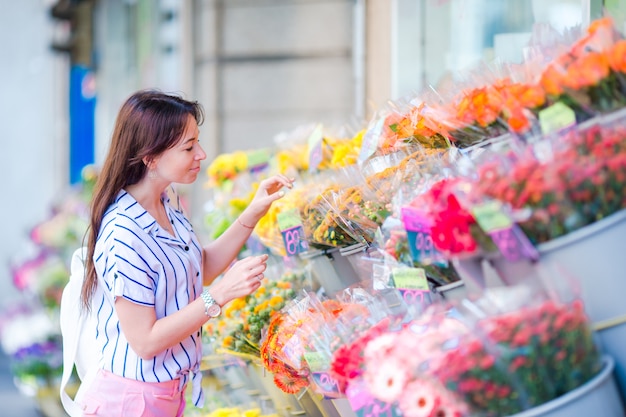 Bella giovane donna con capelli lunghi che selezionano i fiori freschi al mercato europeo