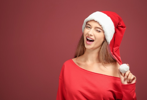 Bella giovane donna con cappello da Babbo Natale su sfondo colorato
