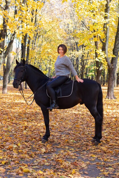 bella giovane donna con cavallo in autunno nel parco