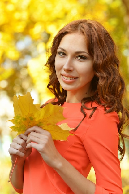 Bella giovane donna con foglie in posa in autunno park