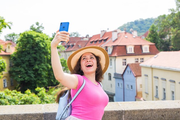 Bella giovane donna con gli occhiali che cammina nella città europea e si fa selfie