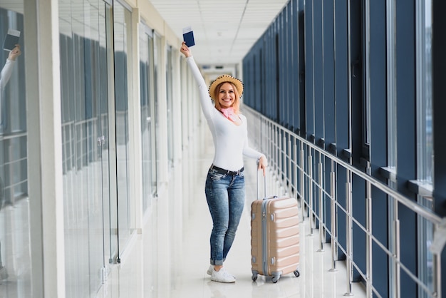 Bella giovane donna con i bagagli in aeroporto