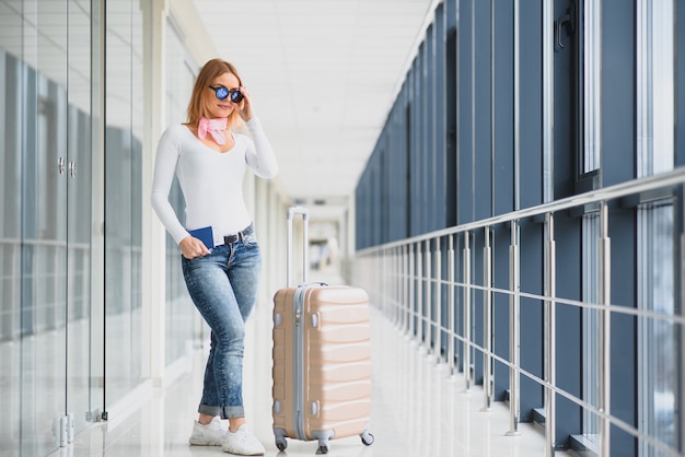 Bella giovane donna con i bagagli in aeroporto