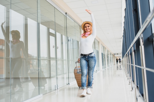 Bella giovane donna con i bagagli in aeroporto