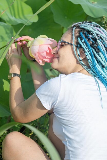 bella giovane donna con i capelli blu afro che si poggia su un pierce di legno sul lago di loto