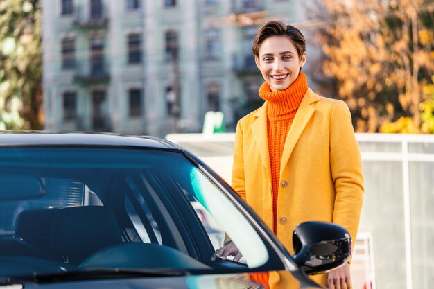 Bella giovane donna con i capelli corti guida l'auto in città