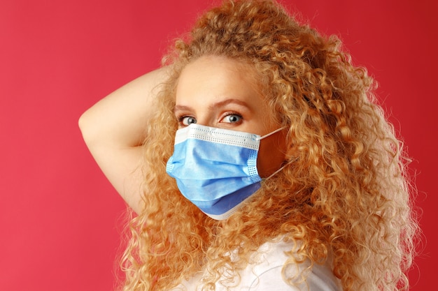 Bella giovane donna con i capelli ricci che indossa la maschera medica