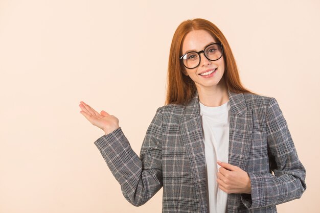 Bella giovane donna con i capelli rossi in una giacca su fondo beige