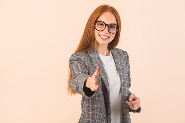 Bella giovane donna con i capelli rossi in una giacca su fondo beige