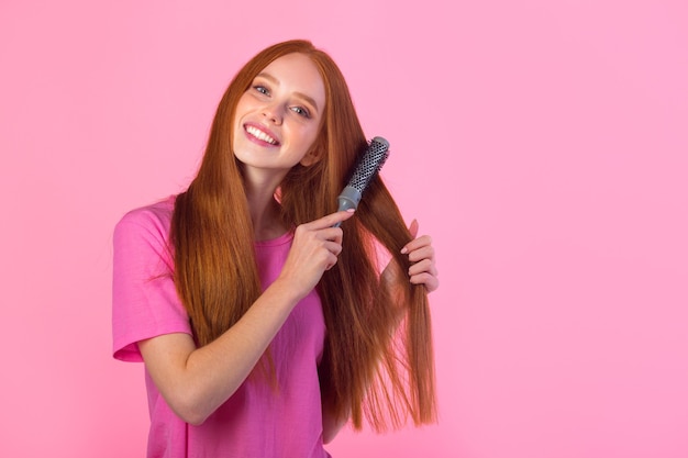 bella giovane donna con i capelli rossi tenendo il pettine