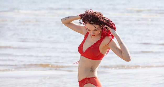 Bella giovane donna con i dreadlocks scarlatti e costume da bagno rosso per godersi la natura.