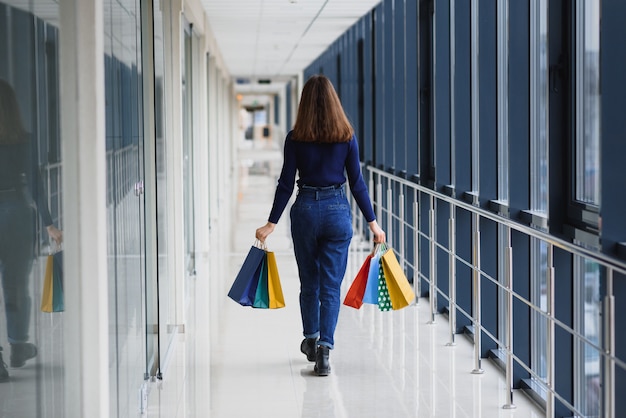 Bella giovane donna con i sacchetti nel centro commerciale