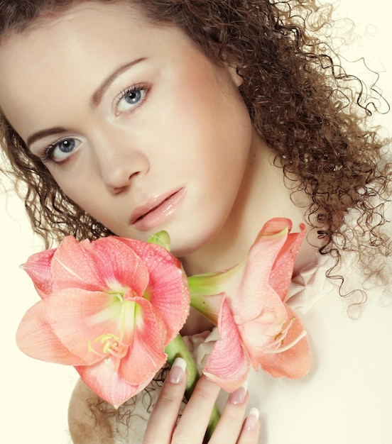 Bella giovane donna con il fiore rosa sopra fondo bianco