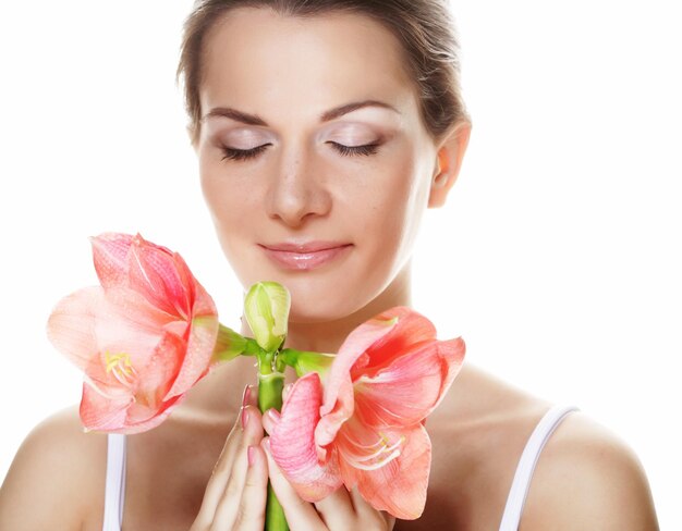 Bella giovane donna con il fiore rosa sopra fondo bianco