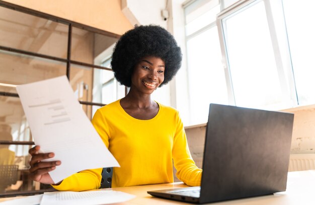 Bella giovane donna con il taglio di capelli afro che lavora in ufficio