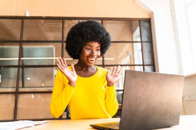 Bella giovane donna con il taglio di capelli afro che lavora in ufficio