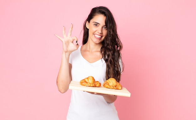 Bella giovane donna con in mano un vassoio di croissant