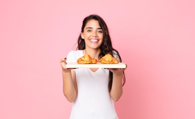 Bella giovane donna con in mano un vassoio di croissant