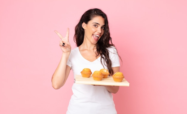 Bella giovane donna con in mano un vassoio di muffin