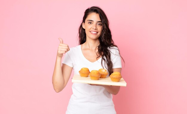 Bella giovane donna con in mano un vassoio di muffin