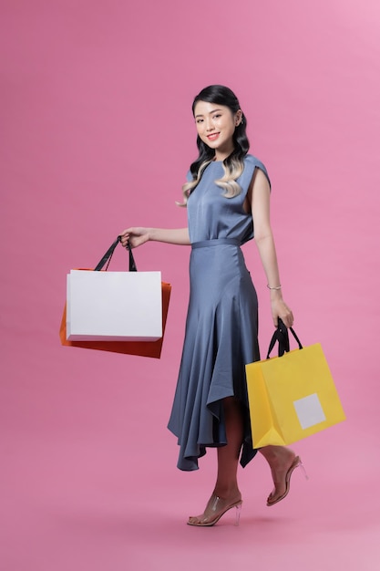 Bella giovane donna con le borse della spesa su sfondo colorato