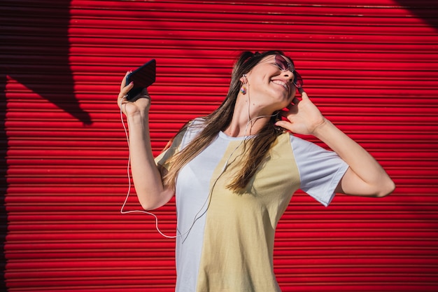 Bella giovane donna con le cuffie all'aperto e godersi la musica.