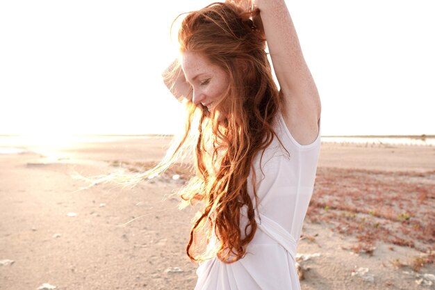 Bella giovane donna con lunghi capelli rossi sani e vestito carino