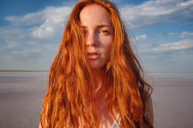 Bella giovane donna con lunghi capelli rossi sani e vestito carino