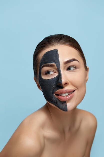 Bella giovane donna con maschera per il viso di argilla nera sulla pelle fresca e pulita Bellezza del modello della ragazza