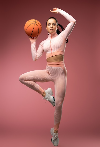 Bella giovane donna con palla da basket che salta in aria