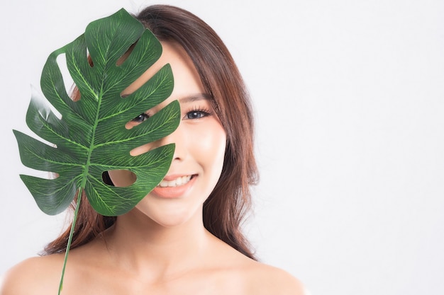 Bella giovane donna con pelle fresca pulita che tiene foglia verde