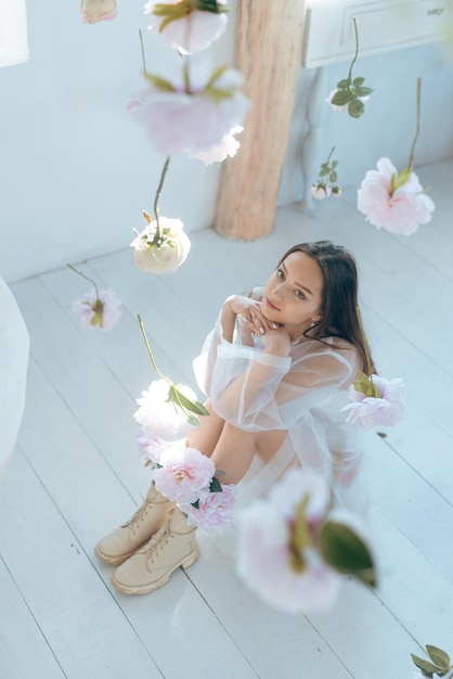 Bella giovane donna con trucco leggero nei colori rosa e capelli biondi su uno sfondo di rose in fiore Ragazza di primavera Concetto di bellezza