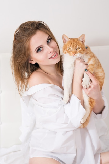 Bella giovane donna con un gatto rosso