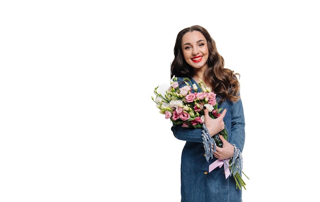 Bella giovane donna con un grande bouquet di fiori che posa sullo sfondo bianco