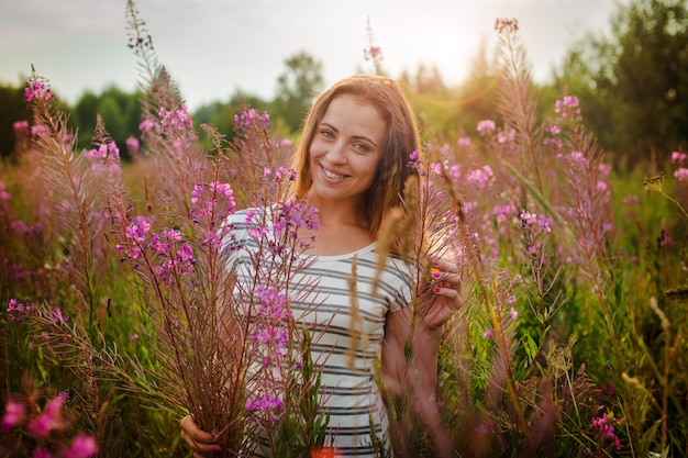 Bella giovane donna con un sorriso felice aggrappato all&#39;erba alta steli erba Kipray